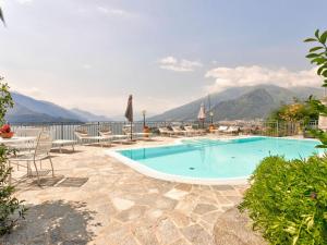 a swimming pool with chairs and a view of mountains at Wonderful flat with swimming pool lift and garden in Gravedona