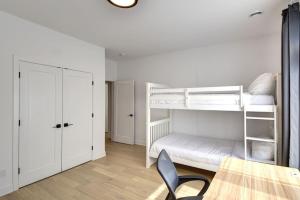 Zimmer mit 2 Etagenbetten und einem Tisch in der Unterkunft 101 Verbier - New 3BR Lux Condo w Mtn View Close to Everything in Mont-Tremblant