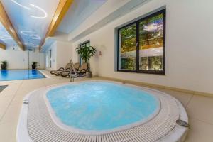 a large swimming pool with a large tub in a room at Dominikana Apartament 41b in Sianozety