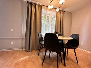 uma sala de jantar com uma mesa e cadeiras e uma janela em Parkside Escape: Stylish 1-BR em Riga
