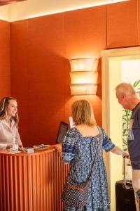 a man and a woman standing at a reception desk at Sentho Roma in Rome