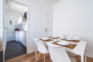 a white dining room with a white table and white chairs at Le cosy - charmant 2 chambres - hyper centre in Reims