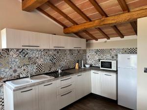 La cuisine est équipée de placards blancs et d'un réfrigérateur blanc. dans l'établissement Cascina Coste, à Roppolo