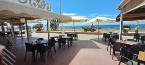 a restaurant with tables and chairs and the beach at Apartamento Don Manuel in Rincón de la Victoria