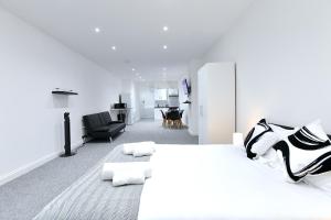 a white bedroom with a large bed and a living room at City Central Apartments in London