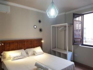 ein Schlafzimmer mit einem großen weißen Bett und einem Kronleuchter in der Unterkunft Apartamentos Alhambra Granada 3000 in Granada