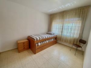 a bedroom with a bed and a chair and a window at AYRES APART in Calafell