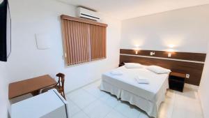 ein Zimmer mit einem Bett, einem Tisch und einem Stuhl in der Unterkunft Hotel Garrafão - Rua Principal de Boituva in Boituva