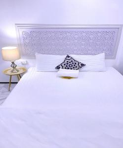 a white bedroom with a white bed and a lamp at Zleepinezz Hostel in Phra Nakhon Si Ayutthaya