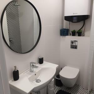 a white bathroom with a sink and a mirror at Holiday Apartment ORA in Balchik