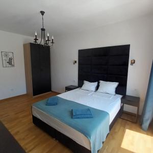 a bedroom with a large bed with a black headboard at Holiday Apartment ORA in Balchik