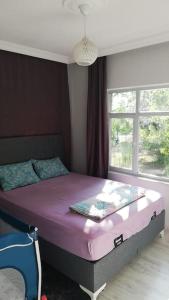 Un dormitorio con una cama con sábanas moradas y una ventana en göl manzarali ılıcaya ve göle 200m uzaklikta, en Boyalıca