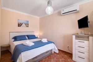 Schlafzimmer mit einem Bett mit blauer Bettwäsche und einem TV in der Unterkunft At-tunis in Tunes