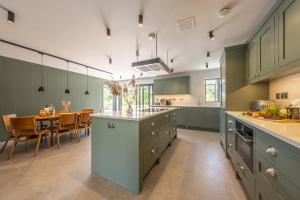 a kitchen with green cabinets and a dining room at The Grain Store in Reepham