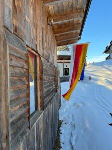 Almhütte - Skihütte am Goldeck in Kärnten في Baldramsdorf: علم معلق على جانب مبنى في الثلج