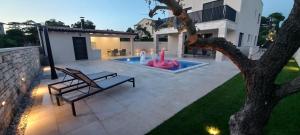 un cortile con piscina, panchina e fontana di Villa Salvore - new luxury house, heated pool, near beaches, playroom - Istria a Savudrija