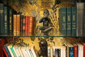 a book shelf filled with books and a statue at Le Pavillon de l'Emyrne in Antananarivo