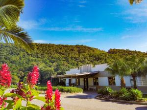 a building with red flowers in front of a mountain at Hotel Termas da Guarda in Tubarão