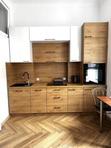 a kitchen with wooden cabinets and a wooden floor at Apartament Szczytna Retro in Toruń