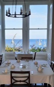 een eetkamer met een tafel en uitzicht op de oceaan bij Mount Royal - Penzance in Penzance