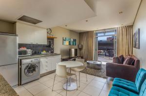 a kitchen and living room with a table and a couch at Harbouredge Suites in Cape Town