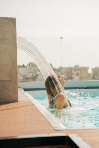 a person is in a swimming pool under a fountain at Athesense Suites in Athens