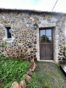a stone house with a wooden door and a window at Le Repère du Loup in Malbosc