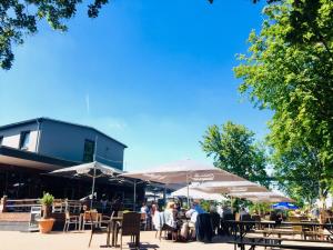 a group of people sitting at tables with umbrellas at Hotel Mintarder Wasserbahnhof in Mülheim an der Ruhr