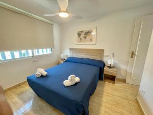 sypialnia z niebieskim łóżkiem i 2 ręcznikami w obiekcie Apartamento turístico Playmon Bacana Planta 13 w mieście Benidorm