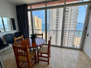 jadalnia ze stołem i krzesłami oraz dużym oknem w obiekcie Apartamento turístico Playmon Bacana Planta 13 w mieście Benidorm