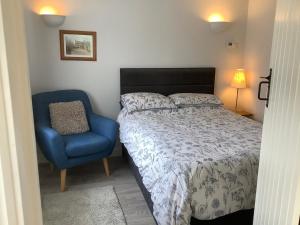 a bedroom with a bed and a blue chair at Hollyhock Cottage, Clematis cottages, Stamford in Stamford