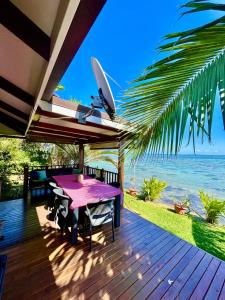 a wooden deck with a table and a view of the ocean at O'coco Bungalow in Paea