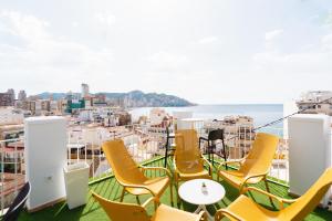 Un balcón con sillas amarillas y vistas al océano. en Hotel Queens - Adults Only en Benidorm