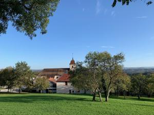 une maison dans un champ avec des arbres au premier plan dans l'établissement La Maison du Fort de Fontain, 