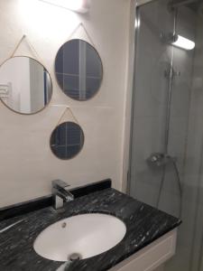 een badkamer met een wastafel en 2 spiegels aan de muur bij La Marginale in Fontevraud-l'Abbaye
