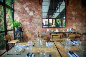 un restaurante con mesas y sillas y una pared de piedra en Le Pavillon de l'Emyrne en Antananarivo