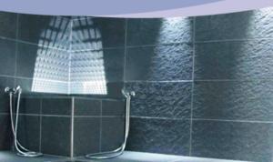 ściana wyłożona czarnymi kafelkami z lustrem w łazience w obiekcie Hotel Dimora Storica La Mirandola w mieście Passo del Tonale