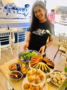 een vrouw die voor een tafel met eten staat bij Zleepinezz Hostel in Phra Nakhon Si Ayutthaya