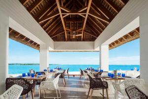 uma sala de jantar com mesas e cadeiras e o oceano em One&Only Le Saint Géran, Mauritius em Belle Mare