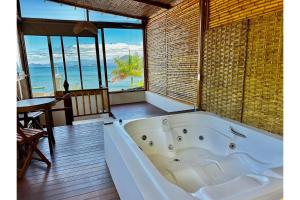 a bath tub in a room with a view of the ocean at OYO Deck Da Villa Pousada Hotel in Picinguaba