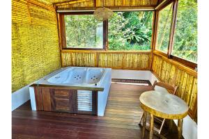 a tub in a room with a table and a window at OYO Deck Da Villa Pousada Hotel in Picinguaba