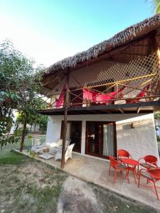 a house with a balcony with red chairs and tables at Bangalôs da Barra Chalé 3 in Barra Grande