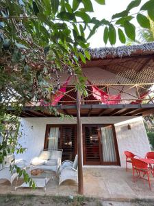 a porch of a house with chairs and a table at Bangalôs da Barra Chalé 3 in Barra Grande