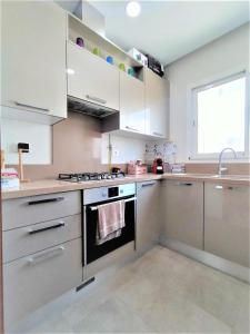 a kitchen with white cabinets and a stove top oven at MN Group Belgium Les Jardins de Carthage book via Airrbnb in Tunis