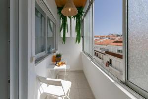 a balcony with a white chair and a table and windows at Seagulls' House in Nazaré