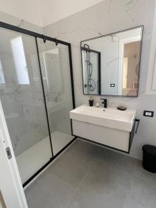 a white bathroom with a sink and a shower at Martanna Rooms in Carini
