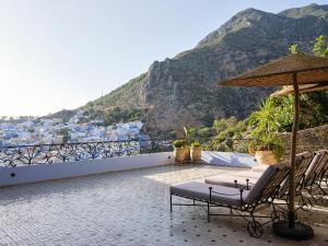 uma vista a partir da varanda de um hotel com cadeiras e um guarda-sol em Dar Jasmine em Chefchaouen