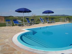 a swimming pool with blue chairs and umbrellas at Cosy agriturismo in Toscana with outdoor swimming pool in Peccioli
