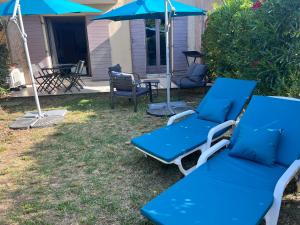 2 blaue Liegestühle, ein Sonnenschirm und ein Tisch in der Unterkunft Appartement T2 avec jardin privé, piscine et barbecue in Lorgues