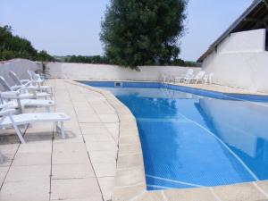 a swimming pool with white chairs next to a white wall at GersGites in Justian +9 photos